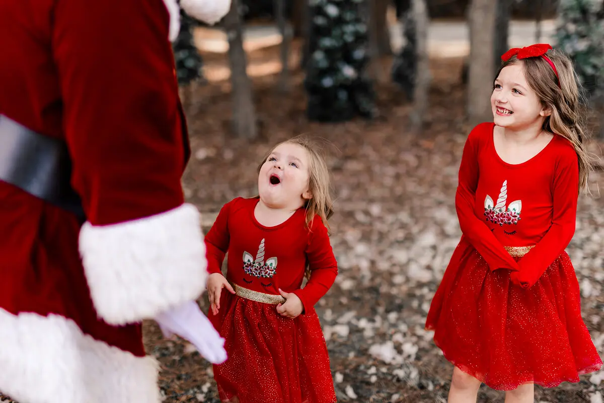Children excitedly meeting Santa in forest.