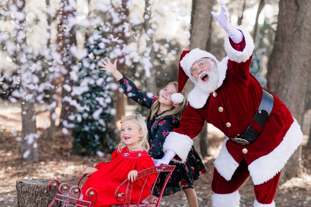 Santa and kids enjoying falling snow outdoors.