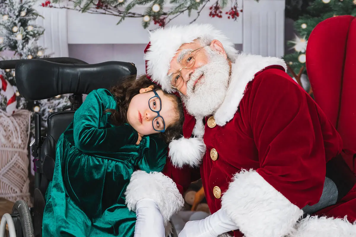 Santa with child in wheelchair, holiday setting.