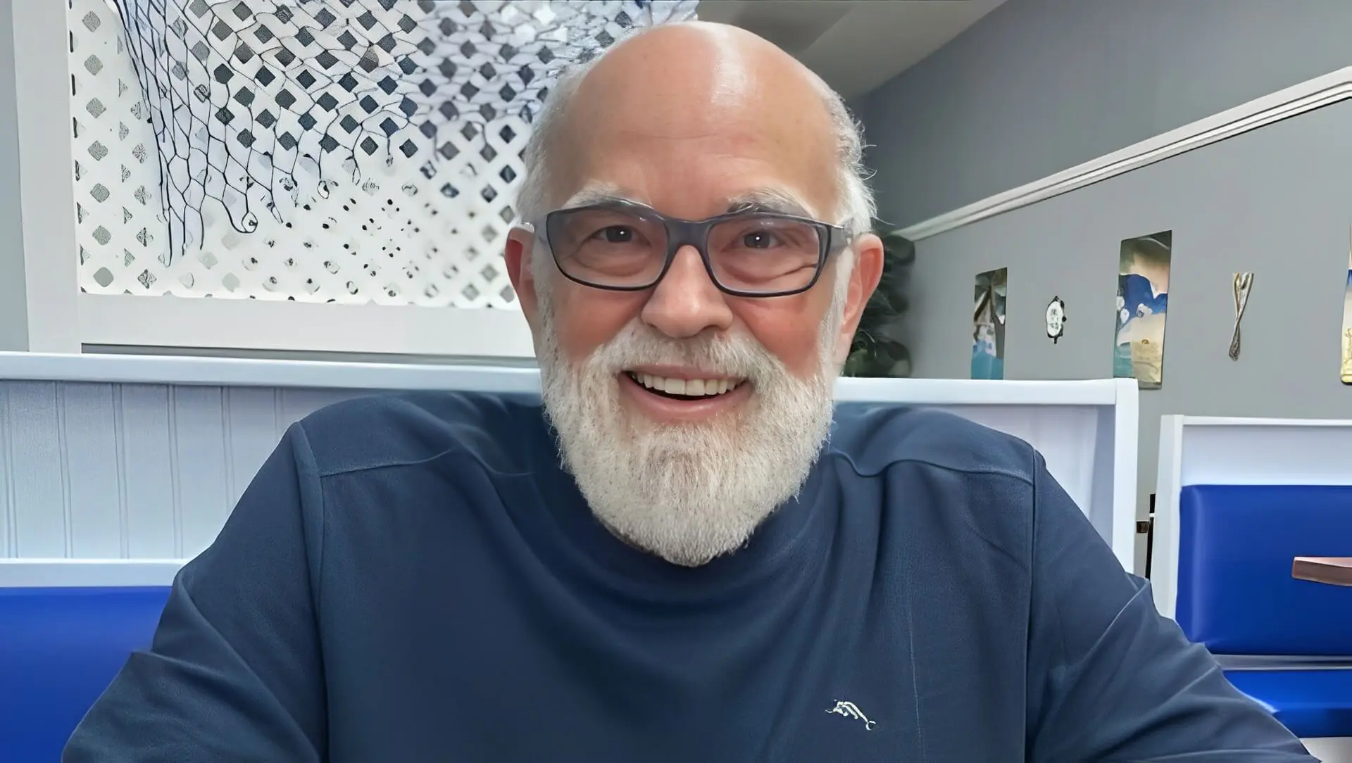 Smiling man with glasses and white beard.