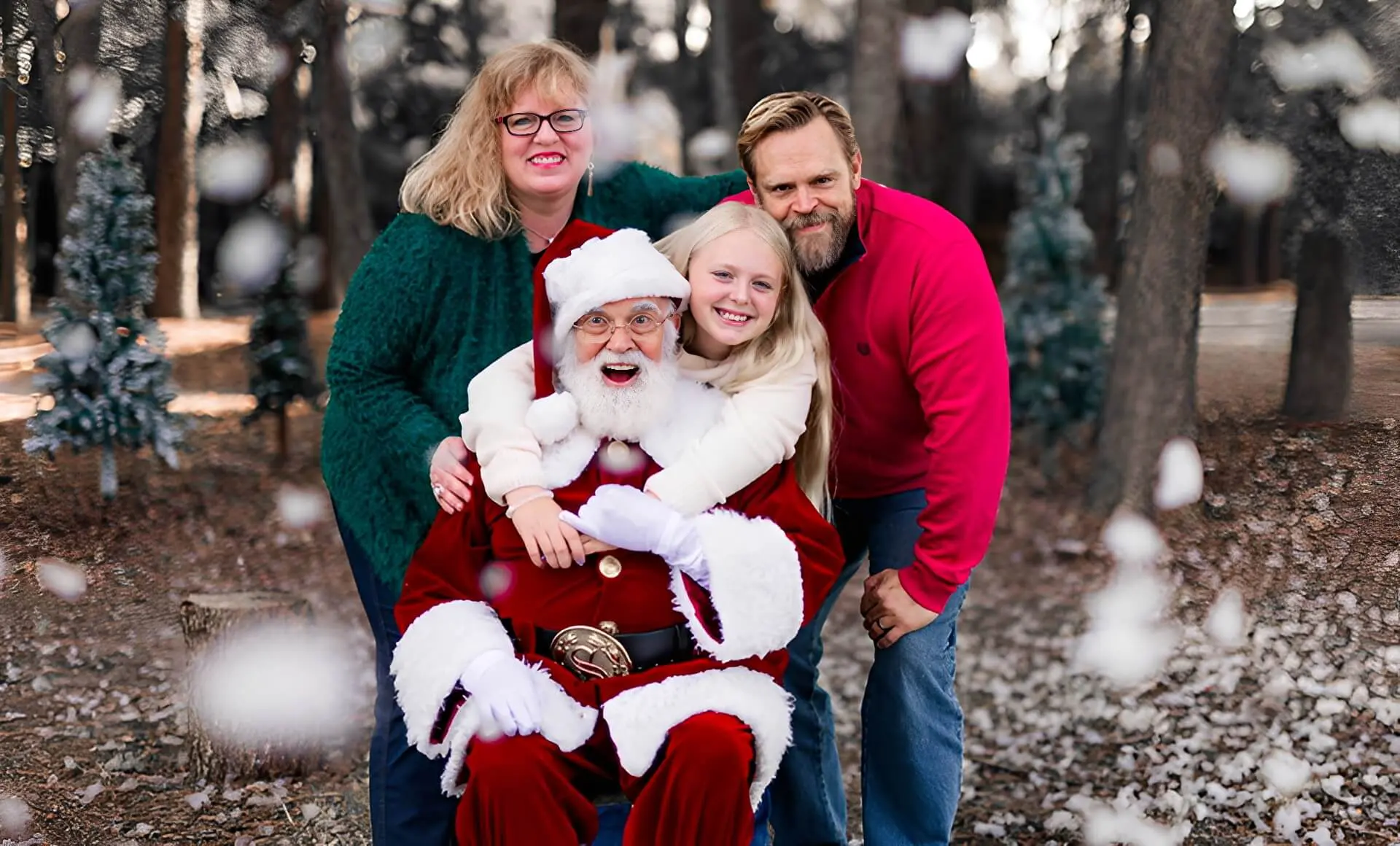 Family posing with Santa in snowy forest.
