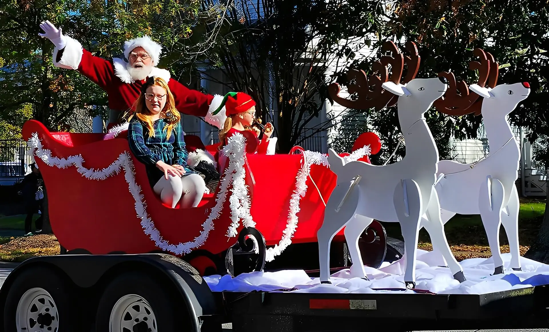 Santa waving from sleigh with reindeer float.