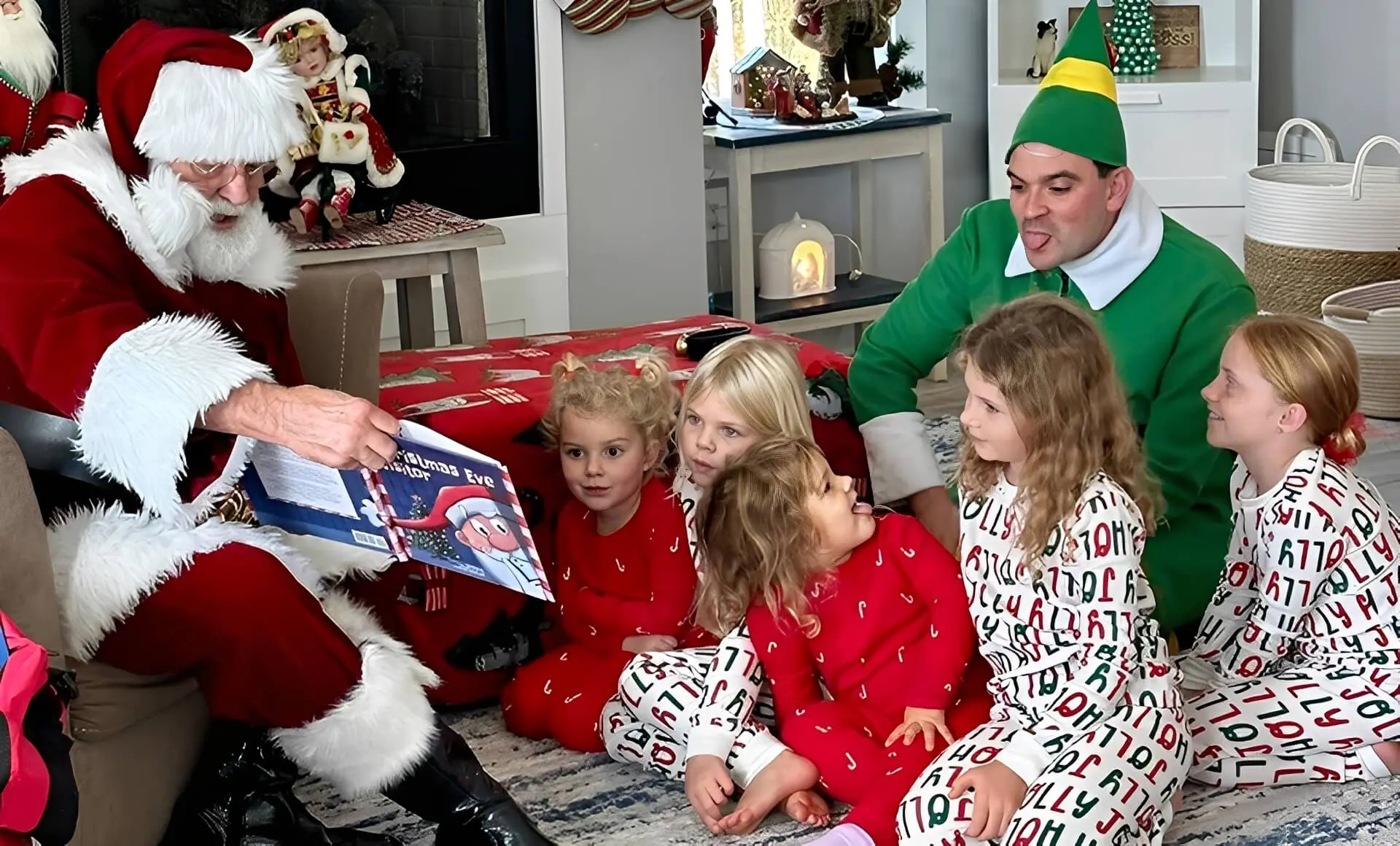Santa reading to children with helper nearby.